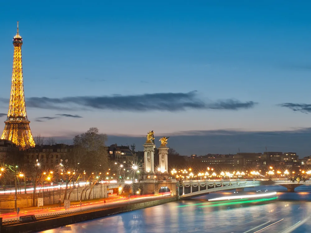 The Eiffel Tower and Pont Alexandre III lit at dusk, on the stretch of the Seine the dinner cruise passes